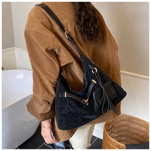Detail of black suede hobo bag with gold buckle and a cute animal charm on shoulder