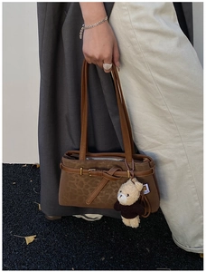 Close-up of caramel leopard print bucket bag with metal buckle and plush bear charm