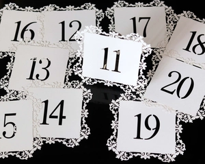 Detail of white laser-cut table number cards 11 to 20 for wedding and banquet events