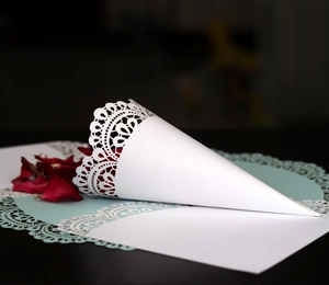 Macro shot of white lace cut-out paper cones for wedding confetti and petals