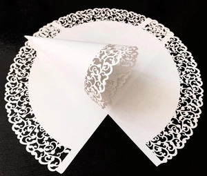 Detail of white laser-cut confetti cone with intricate lace pattern for weddings