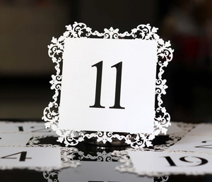 Laser-cut white wedding table card featuring bold black number eleven on reflective surface