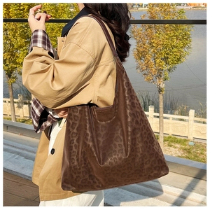 Outdoor shot of a large leopard print tote bag paired with a classic khaki trench coat