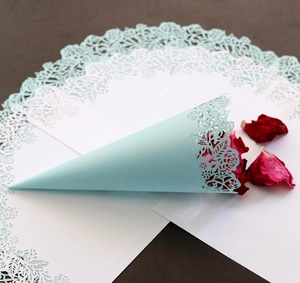 Detail of laser-cut rose hollow pattern on light blue paper wedding confetti cone