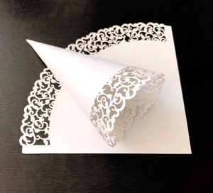 Detail of laser cut lace patterns on white paper wedding confetti petal cones
