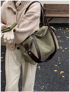 Detail of olive green canvas tote bag with brown strap and silver zipper in autumn setting