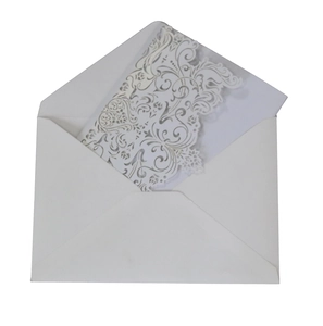 Detail of laser-cut white wedding invitation with intricate floral lace and matching envelope