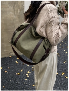 Detail of army green canvas tote bag with brown leather straps shown on a female model