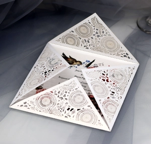 Elegant laser-cut wedding invitation with white floral bird design and blue tulle decor