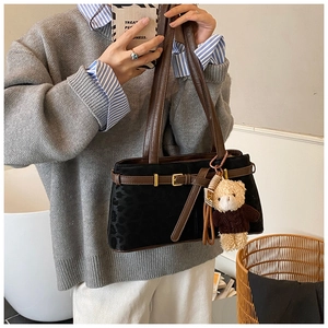 Detail of leopard print bucket bag with brown leather strap and a cute teddy bear charm