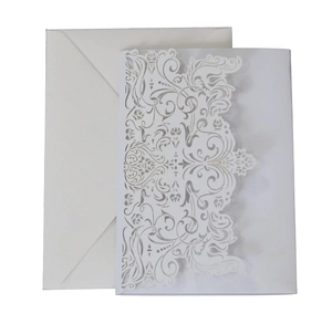 Intricate laser-cut lace pattern detail on elegant white wedding invitation envelope