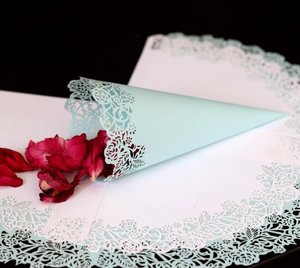Detail of laser-cut flower pattern on light blue paper confetti cones for weddings