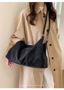 Bolso hobo minimalista de cuero negro mate con correa ajustable y abrigo beige