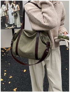 Detail of olive green canvas tote bag with brown leather straps and side zipper pocket
