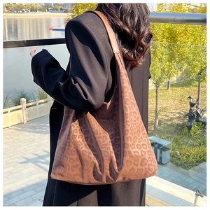 Detail of leopard print tote bag in soft suede fabric worn over a black blazer