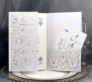 Detailed laser-cut white wedding invitation with floral inner card on an elegant tray