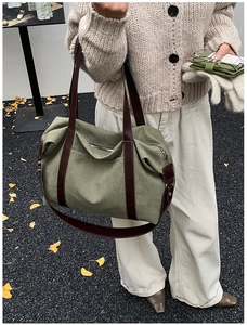 Detail of army green canvas tote bag featuring premium brown leather handles and silver zipper