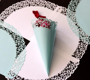Detailed laser-cut mint green confetti cone with intricate floral patterns for weddings