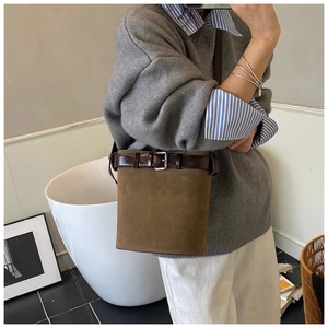 Detail showing the brown suede bucket bag with leather drawstring and metal buckle closure