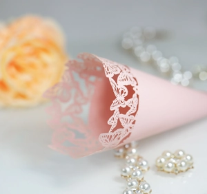 Close-up of pink laser-cut hollow butterfly wedding paper petal cone for party decor