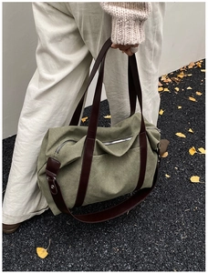 Detail of olive canvas tote bag with brown leather handles and functional front zipper