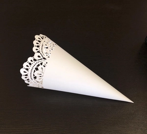 Detailed view of the laser-cut white lace edge on a cone-shaped wedding paper holder