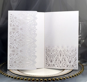 Detail showing laser-cut lace pattern on white pearlescent wedding invitation card