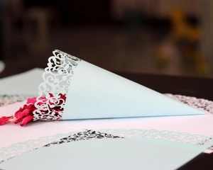 Close-up of laser-cut hollow pattern on light blue paper wedding confetti cone with dried petals