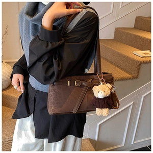 Detail of dark brown leopard bucket bag with vintage texture and plush bear pendant