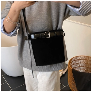 Black bucket bag with matte finish and silver belt buckle detail in lifestyle setting