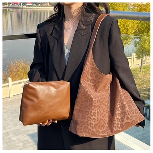 Detail of leopard print hobo bag and brown leather pouch combo shown with black blazer