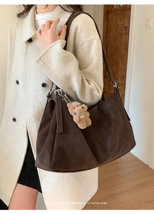 Detalle de bolso tote marrón oscuro en ante sintético con colgante de oso de peluche
