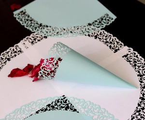 Detail view of mint green laser-cut wedding confetti cones with floral vine pattern
