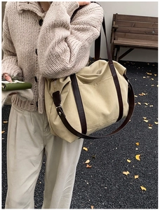 Detail of large canvas tote bag with brown leather handles in outdoor autumn setting