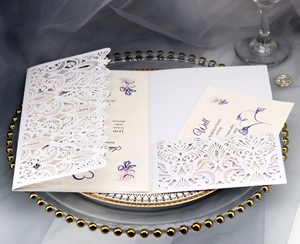 Detail of laser-cut wedding invitation featuring intricate hollow floral patterns on white paper