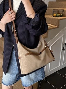 Minimalist khaki tote bag with leather trim and gold buckle shown on a female model