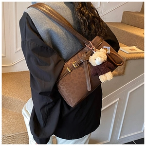 Detail of leopard print bucket bag with gold buckle and cute brown plush bear charm