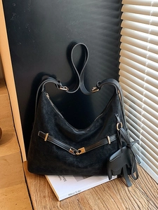 Elegant black suede tote bag with gold hardware and horse charm on a wooden table
