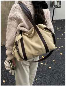 Large khaki canvas tote bag shown from behind on a shoulder in autumn outdoor setting