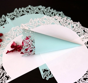 Close-up of mint green laser-cut wedding petal cone with butterfly patterns