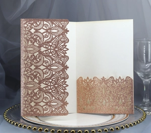 Detail of rose gold laser cut lace invitation with fine glitter texture on a tray