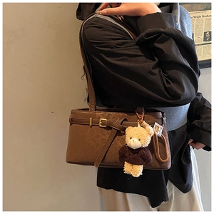 Close-up of vintage brown leopard bucket bag with leather strap and cute bear charm