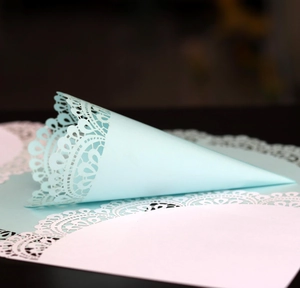 Detail of laser-cut lace pattern on light blue wedding paper petal cone for confetti