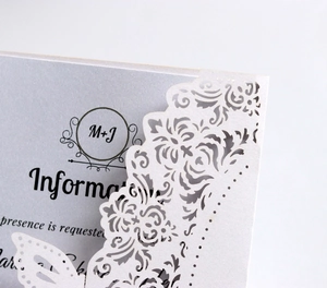 Detail of silver laser-cut wedding invitation with pearl texture and butterfly accent