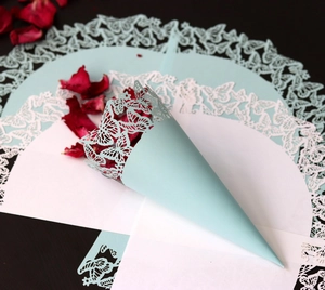 Light blue laser-cut paper cone with butterfly design filled with red rose petals