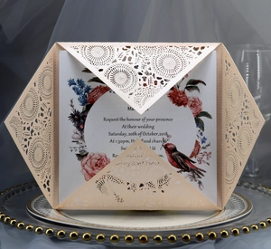 Detail of laser-cut champagne gold wedding invitation with floral and robin inner card