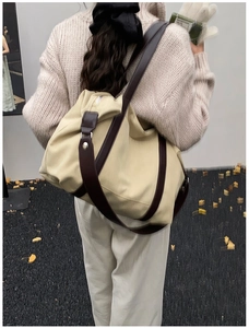 Detailed back view of a large beige canvas tote bag with brown leather straps and zipper