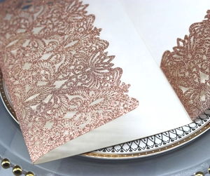 Macro detail of laser-cut rose gold glitter wedding invitation with floral patterns