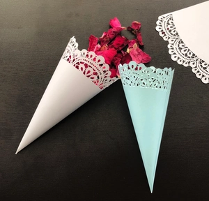 Macro detail of laser-cut lace pattern on white and blue wedding petal paper cones