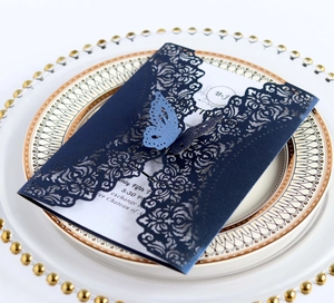 Detail of navy blue laser-cut wedding invitation with elegant butterfly and floral patterns